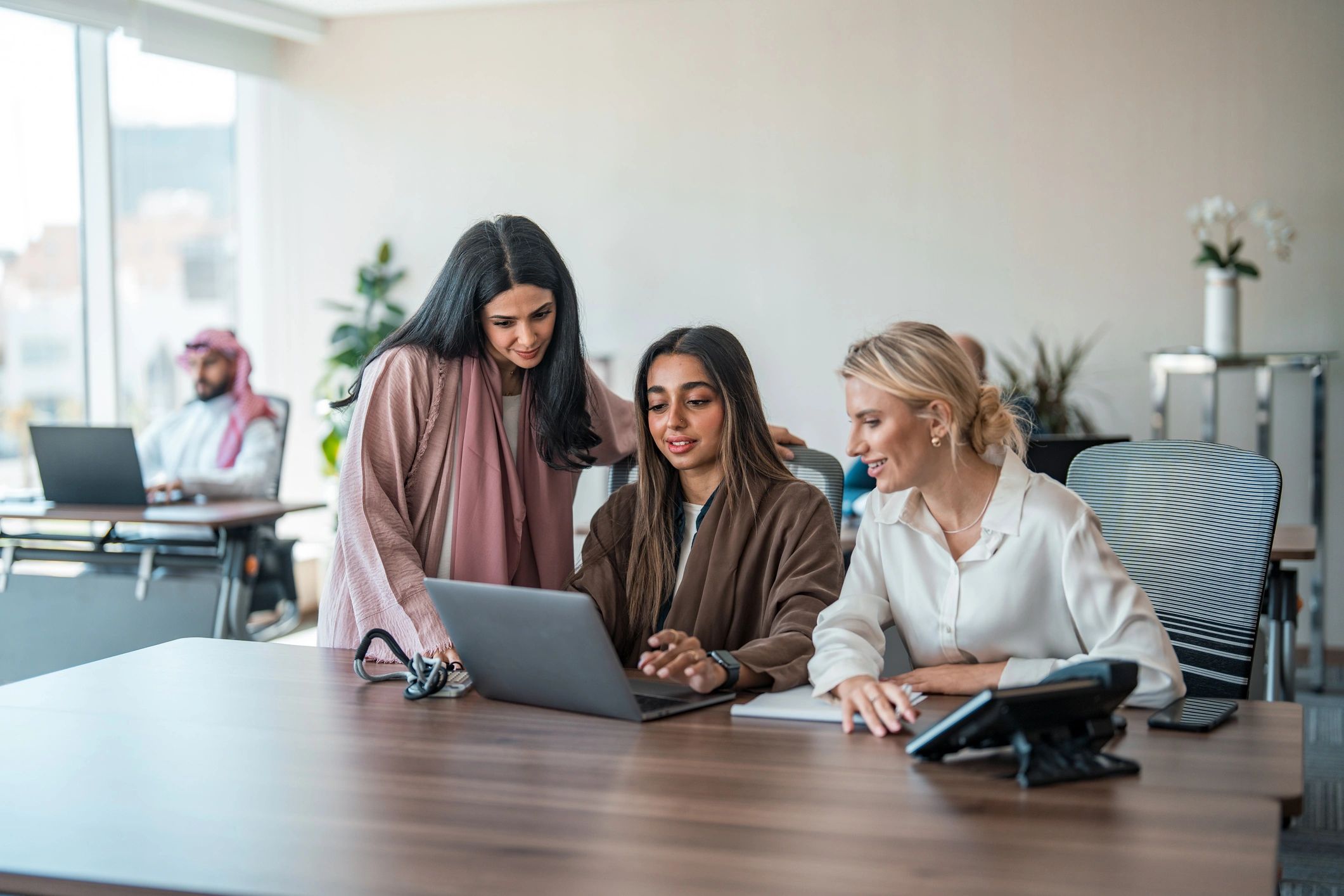 Professional business support team collaborating with laptops in a modern office